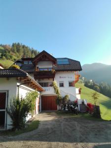 a white house with a gate and mountains in the background at Agritur Bolser in San Vigilio Di Marebbe