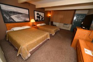a hotel room with two beds and a television at Costa Mesa Inn - Newport Beach Area in Costa Mesa