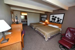 a hotel room with two beds and a desk at Costa Mesa Inn - Newport Beach Area in Costa Mesa