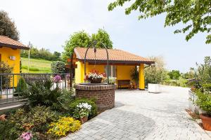 a yellow house with a patio with a flower garden at Osteria da Cesare e Locanda in Castel San Pietro Terme
