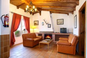 een woonkamer met 2 stoelen en een open haard bij casa del gastronomo in Cortes de la Frontera