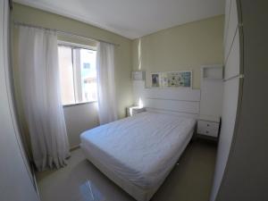 ein Schlafzimmer mit einem weißen Bett und einem Fenster in der Unterkunft A105 Praia Mar 250 metros Bombas in Bombinhas