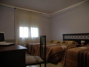 1 Schlafzimmer mit 2 Betten und einem Laptop auf einem Schreibtisch in der Unterkunft Hostal Oasis in Fraga