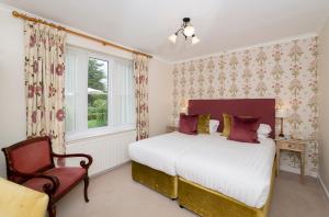 a bedroom with a bed and a chair and a window at Three Ways House Hotel in Chipping Campden +83 photos