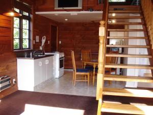 a kitchen and dining room with a spiral staircase in a cabin at Alpine Holiday Apartments & Campground in Hanmer Springs
