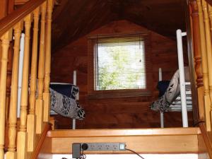 a room with a staircase in a wooden cabin with a window at Alpine Holiday Apartments & Campground in Hanmer Springs