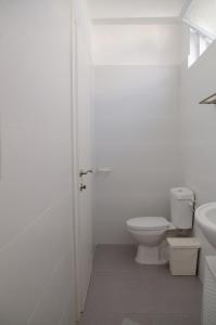 a white bathroom with a toilet and a sink at Hostel BU93 in Tel Aviv