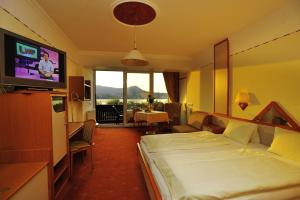 a hotel room with a bed and a flat screen tv at Landhotel Grünberg am See in Gmunden