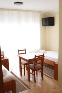 Zimmer mit einem Tisch und Stühlen sowie einem TV in der Unterkunft Rooms Villa Aria in Sesvete