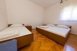 zwei Betten in einem Zimmer mit Holzboden in der Unterkunft Apartments Sunset Dolac in Primošten