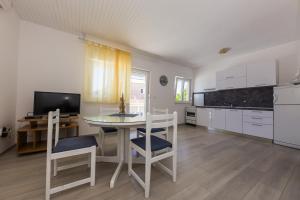 eine Küche mit einem Tisch und Stühlen sowie einem TV in der Unterkunft Apartments Sunset Dolac in Primošten + 21 Fotos