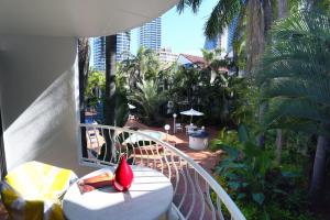 un balcón con una mesa y una flor roja. en St Tropez Resort, en Gold Coast