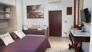 アマルフィにあるLa Casarellaのベッド2台、デスク、テレビが備わる客室です。