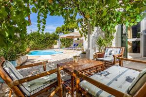 Un patio con sillas y una mesa y una piscina. en Villa Rosada, en Vela Luka