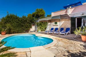 a swimming pool with chairs and a house at Villa Rosada in Vela Luka