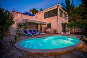 a swimming pool in front of a house at Villa Rosada in Vela Luka