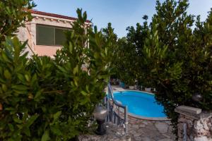 a swimming pool surrounded by trees and a house at Villa Rosada in Vela Luka
