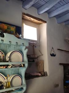 a room with a shelf with plates and a window at Traditional Medieval Stone house in "Ano Syros" in Ano Syros