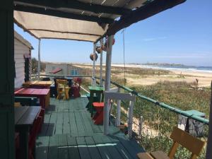 嘉波波洛尼奧的住宿－La Cañada Cabo Polonio，海滩上带桌子和长椅的甲板