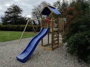 a wooden playground with a blue slide at Rosengaard holiday apartment and B&B in Bramming