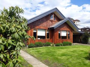 uma casa de madeira com um quintal verde em Patagonia Route B&B em Puerto Varas