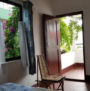 a room with a chair and a door and a window at Bhaskar Homestay in Dibrugarh