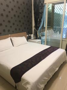 金寧鄉的住宿－愛玩客107，卧室配有一张大白色床和窗户