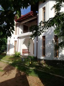 ein weißes Haus mit einer Bank im Hof in der Unterkunft Air Port 5 Minutes Super Clean Upul in Negombo