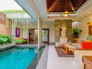 a villa with a swimming pool and a living room at The Kasih Villas & Spa in Seminyak
