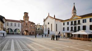 Un gruppo di persone che camminano per la piazza della città di Casa Mian a Oderzo