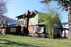 a log cabin with a tree in front of it at Alhue Patagonia Hostel in San Martín de los Andes
