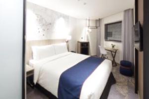 Holiday Inn Express Seoul Hongdae, an IHG Hotel في سول: غرفة نوم بسرير كبير مع بطانية زرقاء