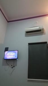 a room with a tv and a air conditioner on a wall at Homestay dan Kost 78 in Jepara