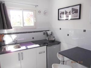 uma cozinha com armários brancos, um lavatório e uma janela em Gîte Studio Tarbes Pyrénées em Tarbes
