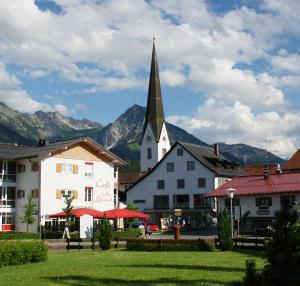 a church with a steeple in a town with mountains at Ferienwohnungen Alpentraum - freiSicht in Fischen