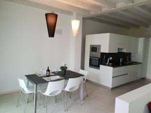 a kitchen with a dining table and white chairs at Deluxe Apartments Garda in Sirmione