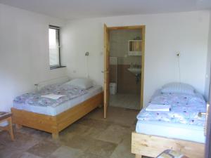 two beds in a room with a bathroom at Herold Panzió in Dunabogdány