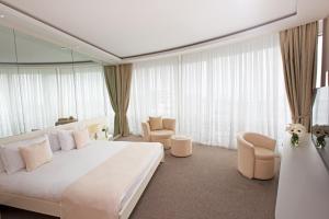 Sahil Hotel Baku في باكو: غرفة في الفندق سرير أبيض كبير وكراسي