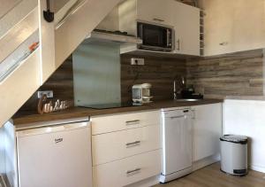 eine kleine Küche mit weißen Schränken und einer Mikrowelle in der Unterkunft Appartement Cosy in Les Angles