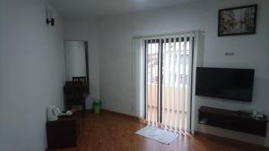 uma sala de estar com uma televisão e uma porta de vidro deslizante em Hotel Mill Road em Malaca