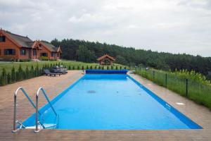 a large blue swimming pool in a yard with a house at Brzezina Resort - Wille in Żnin