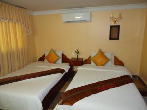 two beds in a hotel room with white sheets at U-Dara Inn Guesthouse in Siem Reap