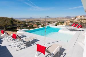 uma vista para uma piscina com cadeiras e uma piscina em Stunning Villa Mistral Private pool em Busot
