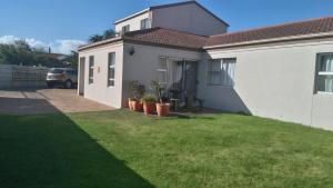 a house with a green lawn in front of it at Bay Breeze Guesthouse Selfcatering in Gordonʼs Bay