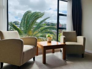 two chairs and a coffee table in front of a window at Boulevard Hotel in Auckland
