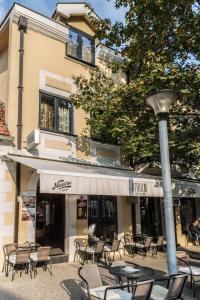 eine Gruppe von Tischen und Stühlen vor einem Gebäude in der Unterkunft GARNI HOTEL ATRIUM in Nikšić