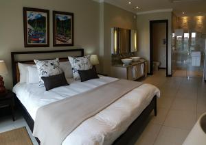 a large white bed in a room with a bathroom at Papay Suite by Simply-Seychelles in Eden Island