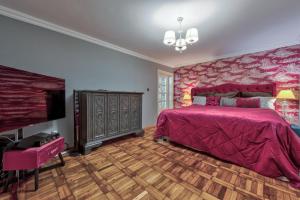 1 dormitorio con 1 cama rosa y TV en Le Park, en Bucarest