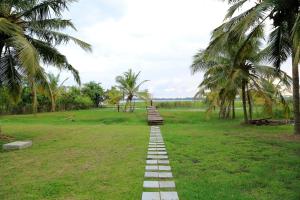 a brick path in a field with palm trees at Tara Watergate in Tissamaharama