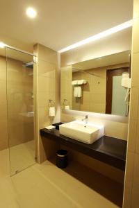 
a bathroom with a sink, mirror, and shower stall at Symphony Suites Hotel in Ipoh
